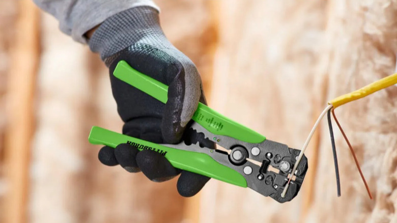 person using green handled wire strippers on wires