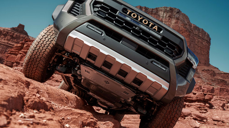 Low front view of grey Toyota Tacoma crawling over red rocks