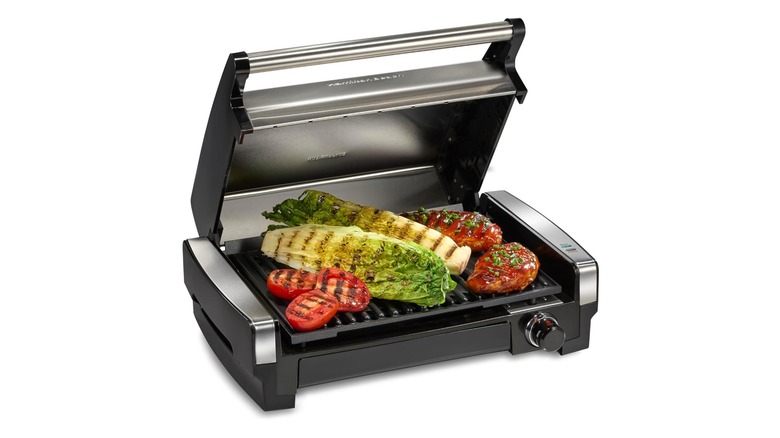 Stock photo of a small compact grill with lid open showing various vegetables