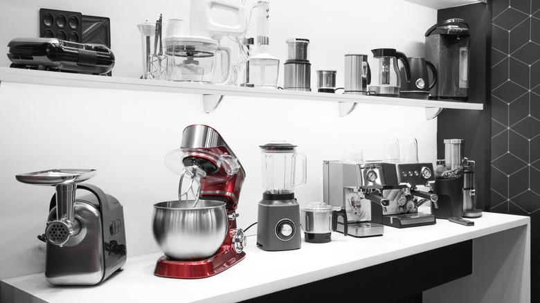 Collection of small appliances on a kitchen countertop and a shelf above the counter