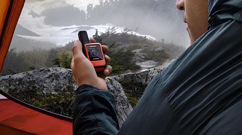 Man holding a compact gps while camping