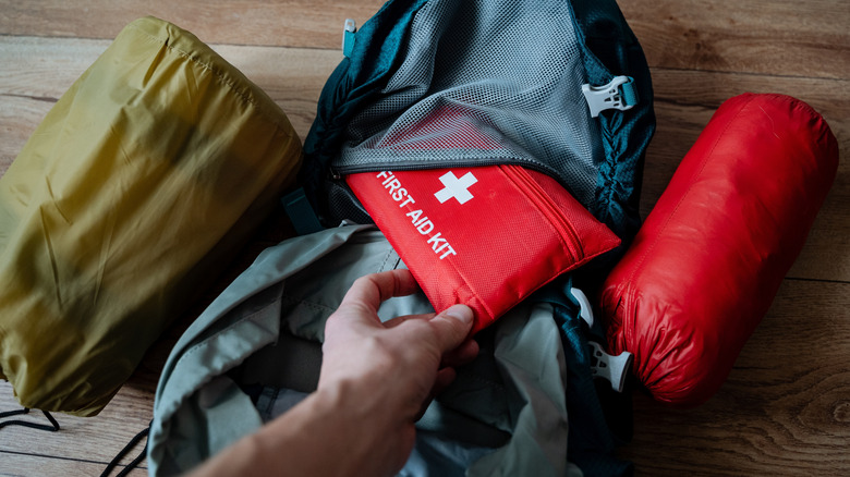 Man pulling out a first aid case from a backpack