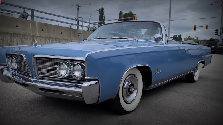 A blue Chrysler Imperial Drophead coupe parked at the side of a road on an overcast day.