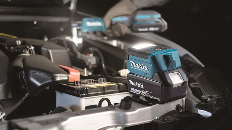 A Makita compact LED light illuminating a vehicle engine bay.