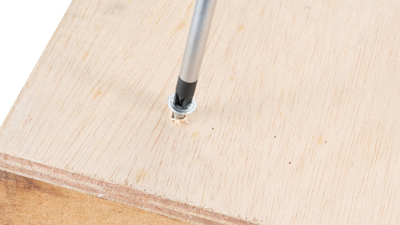 A Makita screwdriver used to drive a screw in wood.