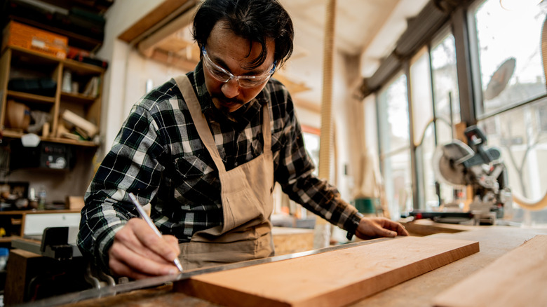 carpenter measuring and marking a board
