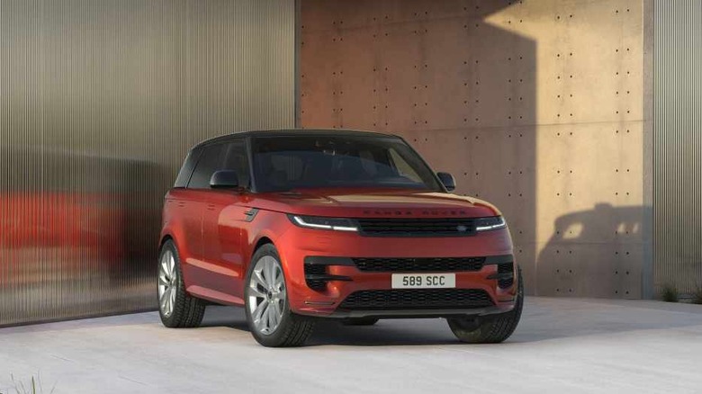 A red 2026 Land Rover Range Rover Sport Twenty Edition SUV standing against a modern beige building.