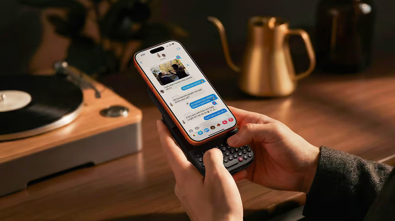 Person holding clicks power keyboard paired to an iphone 16 pro