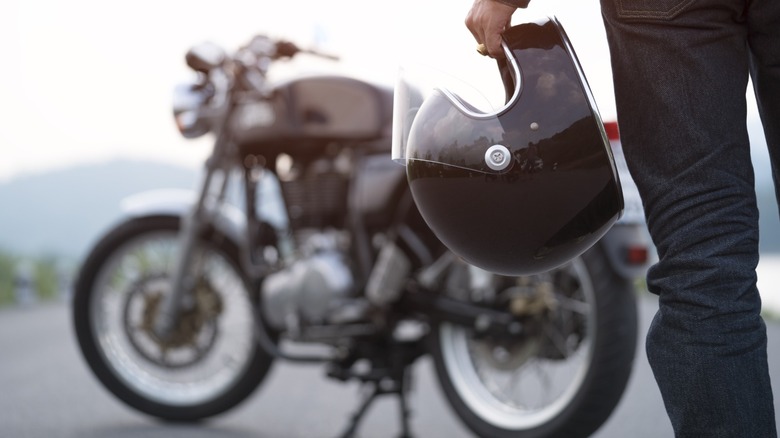 Biker holding helmet with motorcycle in background