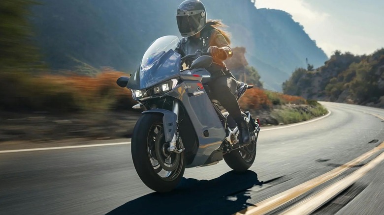 Woman riding a blue Zero motorcycle with blurry background