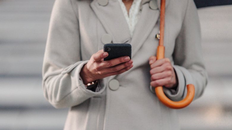 woman holding umbrella and phone