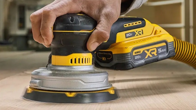 Person sanding table with DeWalt 20V Max XR 6-inch Random Orbital Sander