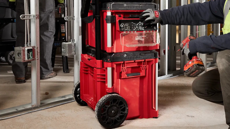 Person reaching into a magnetic tray attached to red Milwaukee Packout boxes