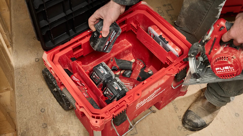 Person storing power tool batteries in a red Milwaukee Packout box