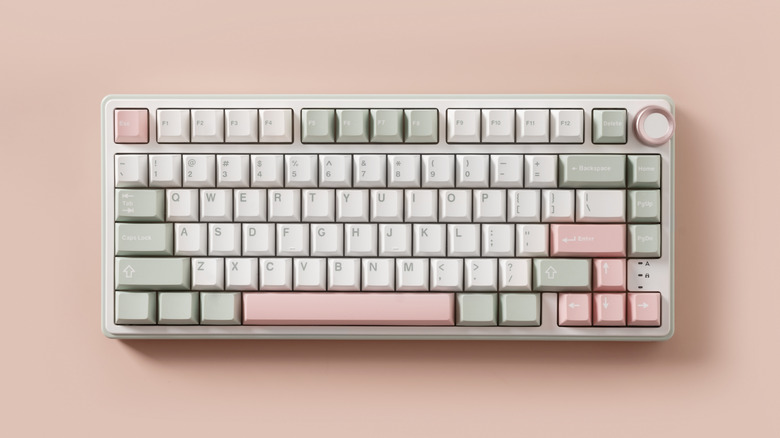 A mechanical keyboard with white, gray, and pink buttons on a pink surface