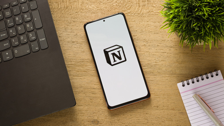 Notion logo on phone next to laptop