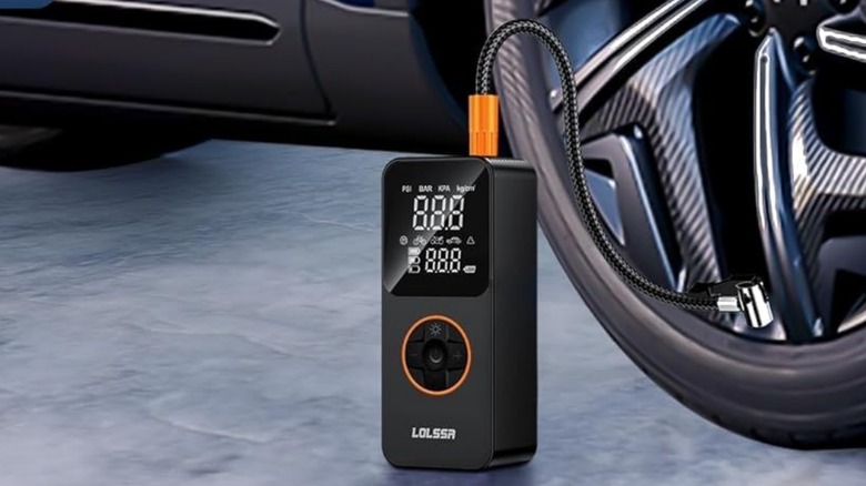 A close-up image of a LOLSSA portable tire inflator being used to fill a tire