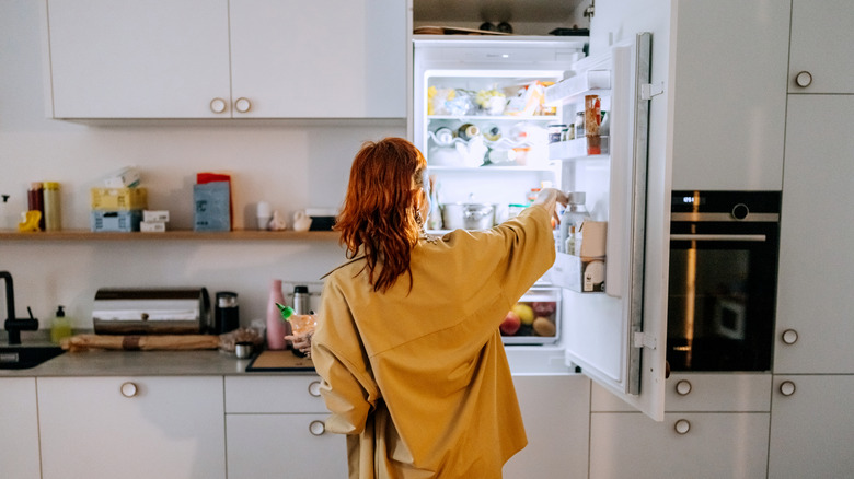 Woman opening a refrigerator in her kitchen