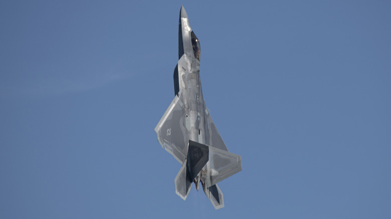 An F-22 with its nose pointed straight up