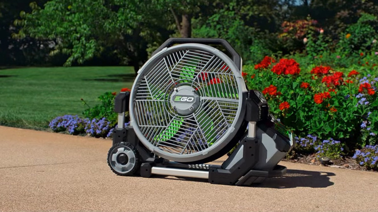 The Ego portable misting fan in front of a patch of flowers