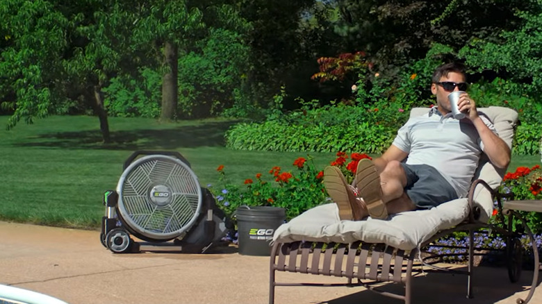 Ego misting fan blowing air and mist onto a man while he lays down in a lawn chair