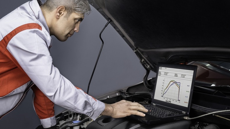 mechanic using laptop connected to car engine