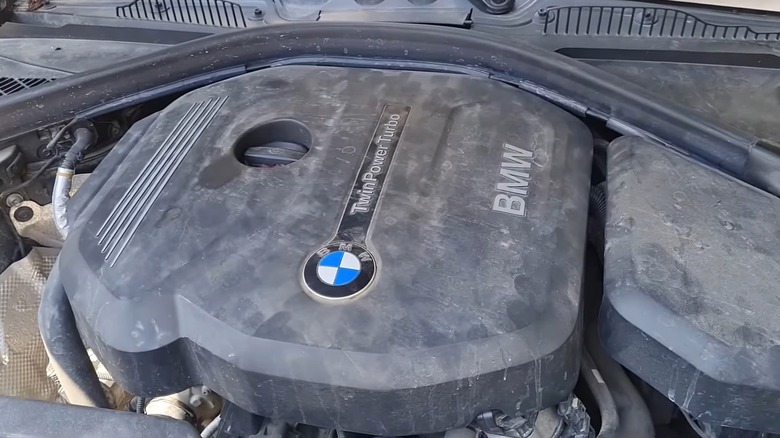 A dusty BMW B38 TwinPower Turbo engine cover sitting under an open hood.