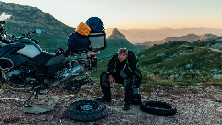 Man sitting beside broken motorcycle.