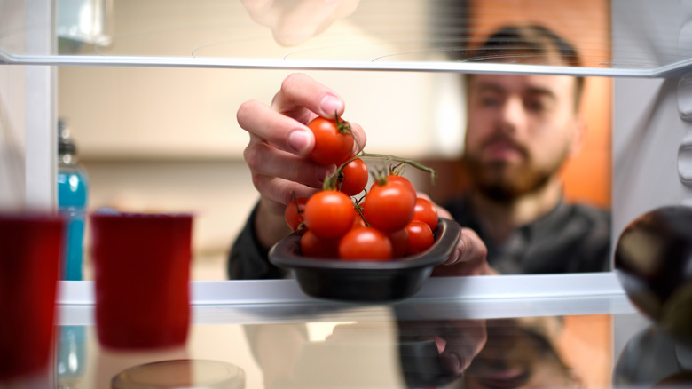 man grabbing cherry tomatoes from fridge