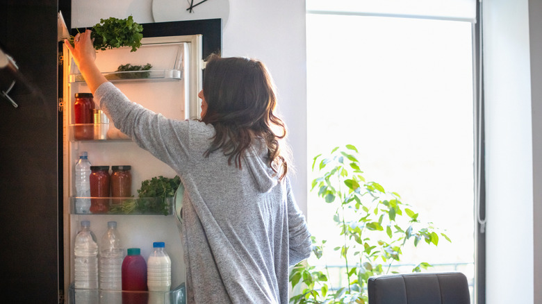 woman taking parsley out of refrigerator