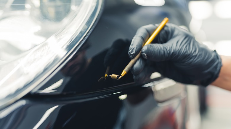 person repairing car paint chip damage