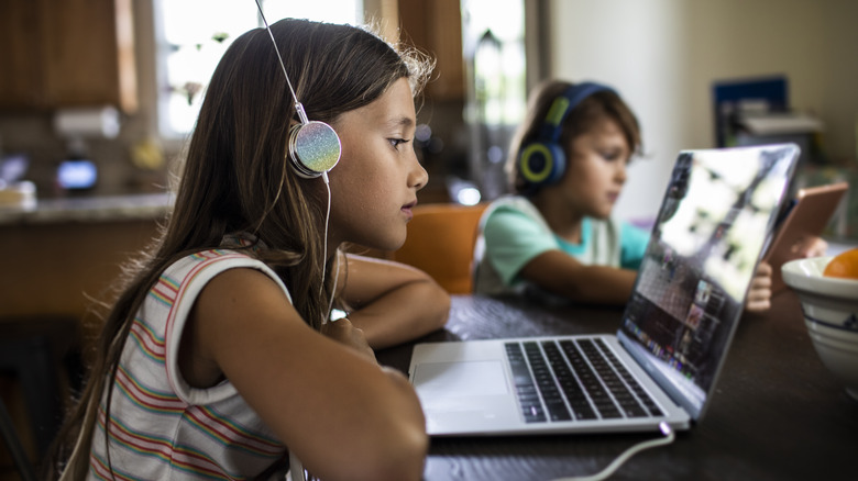 Children with headphones using computers at home