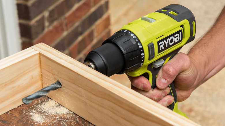 person using ryobi drill