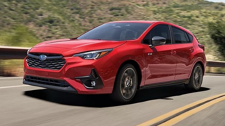 2025 Subaru Impreza driving on a road with a hilly landscape in the background