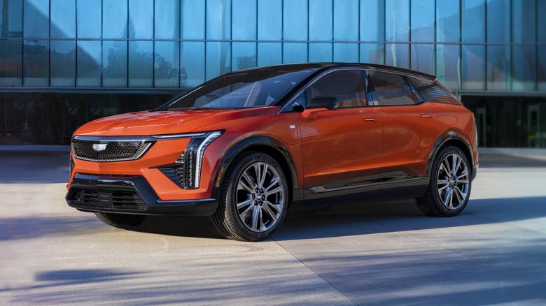 An orange Cadillac Optiq near a modern office building