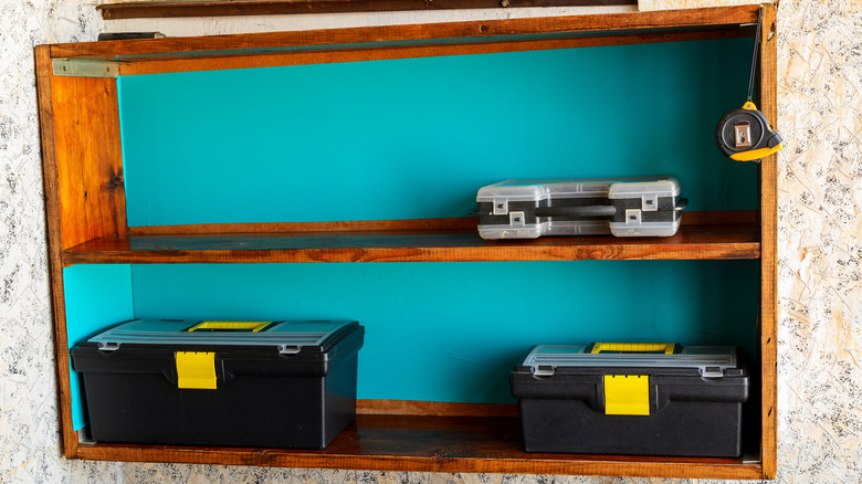 A wooden shelf storing boxes and a tape measure.