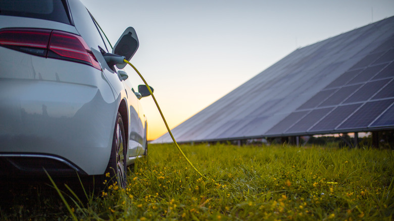 Car charging in front of solar panels
