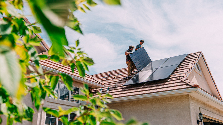 men installing solar panels on roof