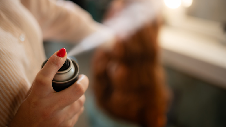 A person spraying an aerosol can in the air.