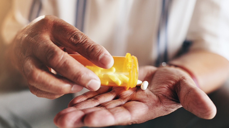 A person pouring pills into their hand.