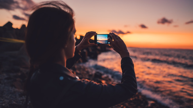woman filming ocean with phone