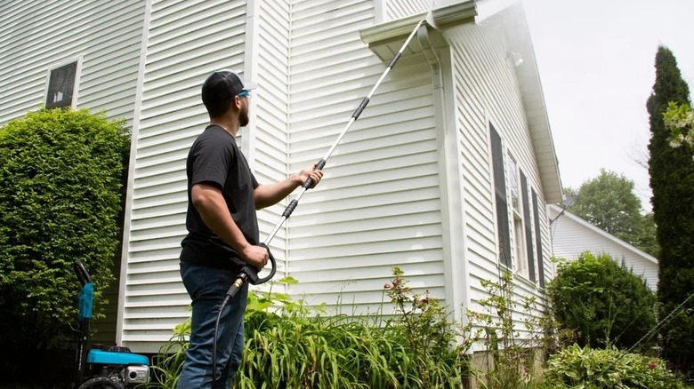 A person using a Surface maxx pressure washer extension wand on their gutter