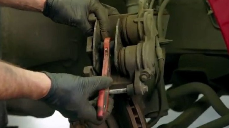 person using pad spreader on brake caliper