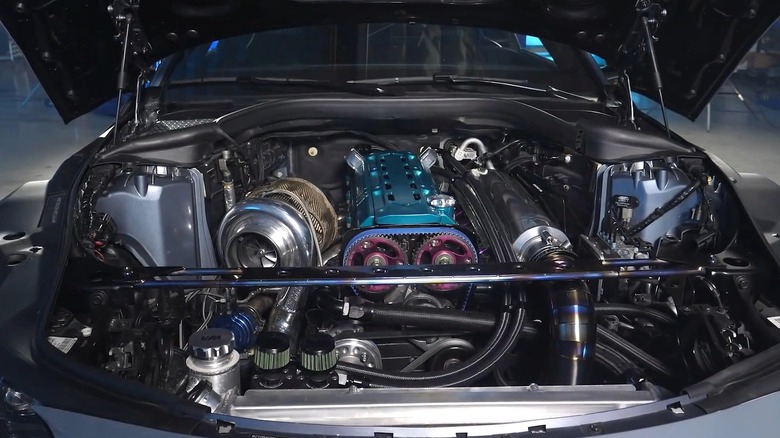 A heavily modified turbocharged inline engine installed in a performance car, featuring a large polished turbo, exposed piping, and upgraded hardware.