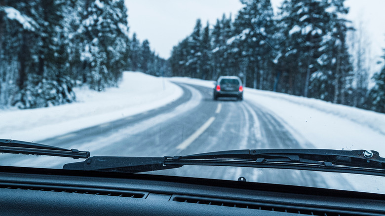Driving through a snowy landscape with a clear windshield.
