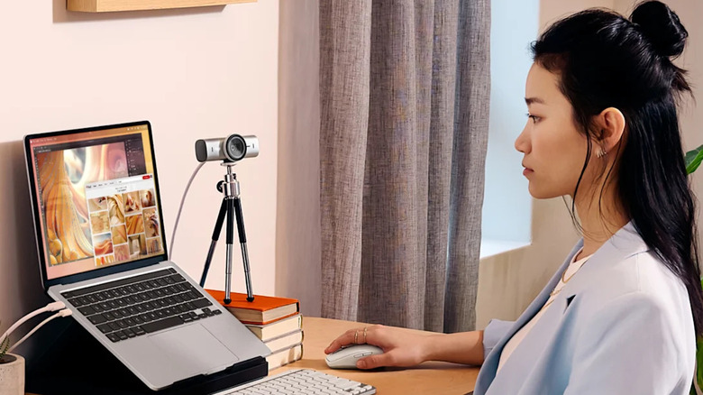 A person using a Logitech webcam with their laptop