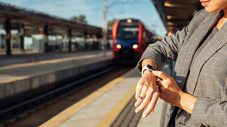 A person using their smartwatch while waiting for the train