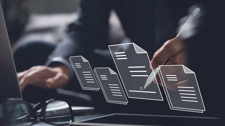 Man writing onto graphics of note icons while using computer