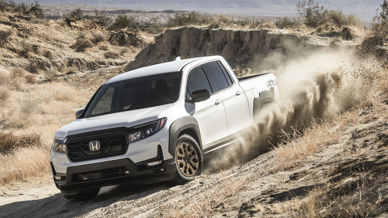 Front 3/4 view of white Honda Ridgeline off-roading in desert.