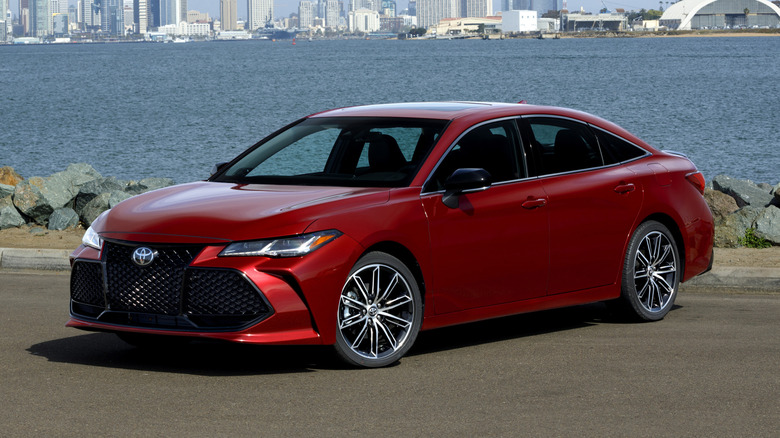 Front 3/4 view of red Toyota Avalon parked in front of harbor.